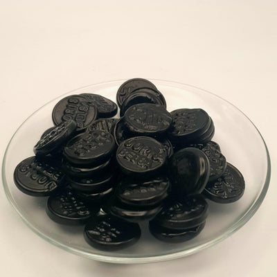 A glass bowl filled with BELGAS black chocolate chips, infused with the rich essence of Letterboxliquorice.