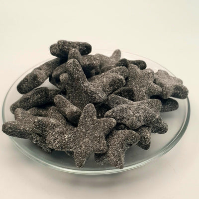 A salty glass plate filled with SALTY SEA STARS shaped cookies for salmiak lovers, from the brand Letterboxliquorice.